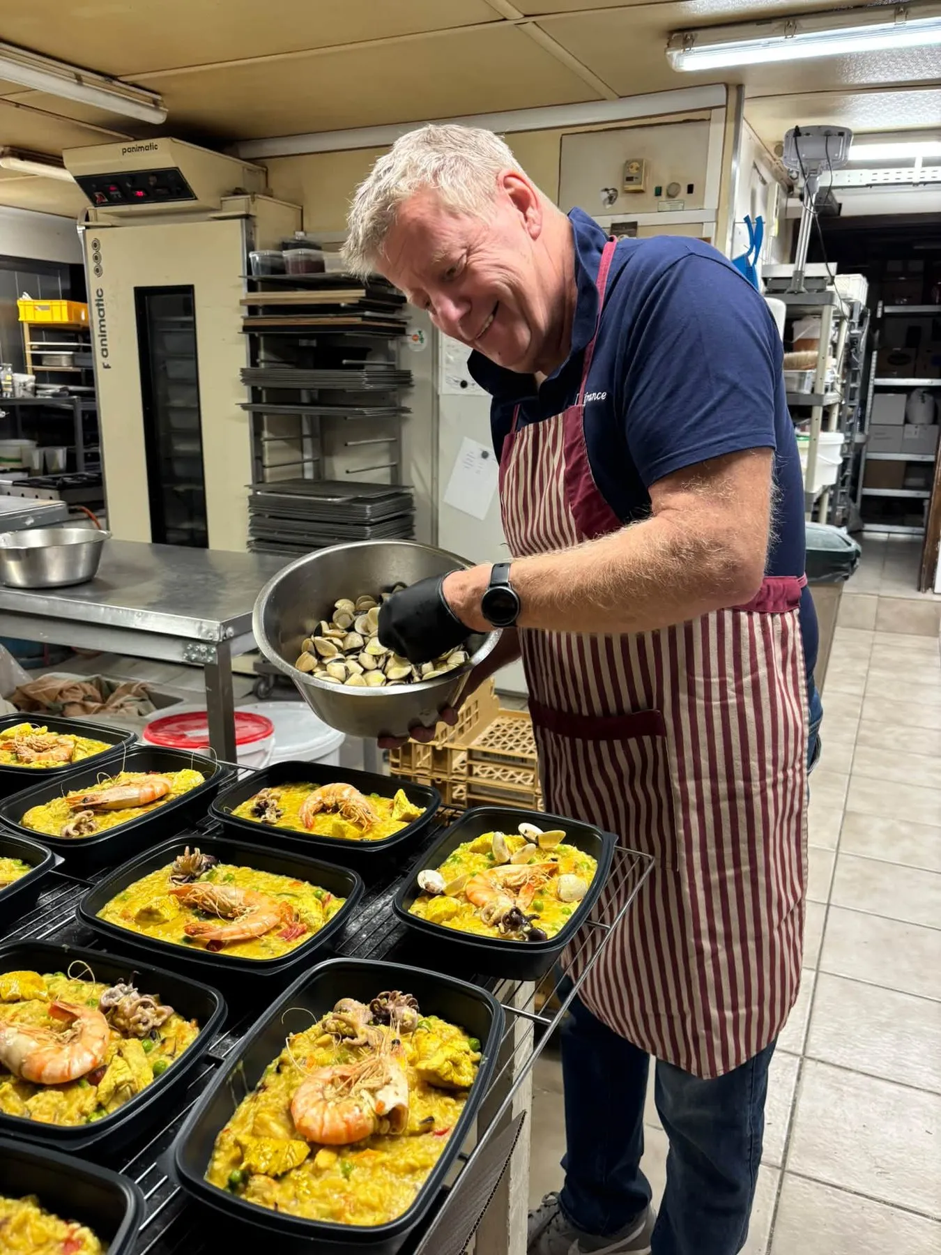 Alain prépare des portions de paella dans l’atelier