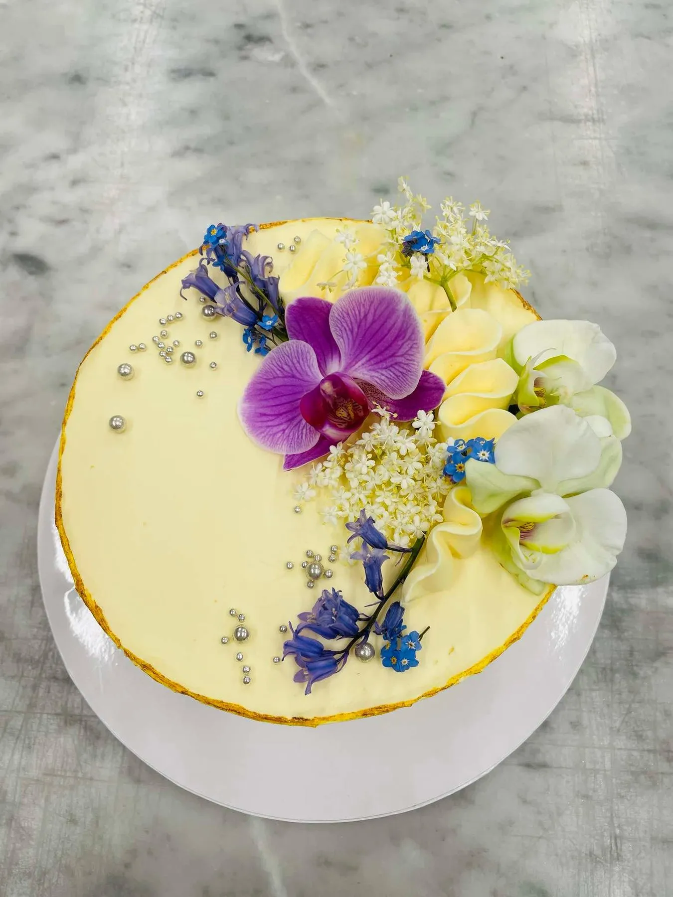 Witte taart versierd met orchideeën en eetbare bloemen